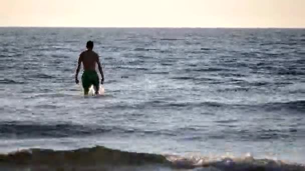 Молодой человек собирается поплавать в море — стоковое видео
