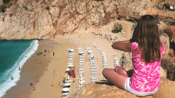 Mujer meditando en acantilado sobre la playa de arena — Vídeo de stock