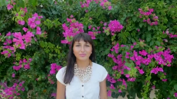 Hermosa mujer en el fondo de la pared de flores — Vídeos de Stock