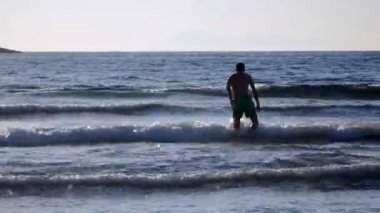 Genç adam denizde yüzecek.