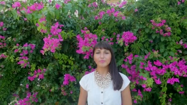 Hermosa mujer en el fondo de la pared de flores — Vídeo de stock