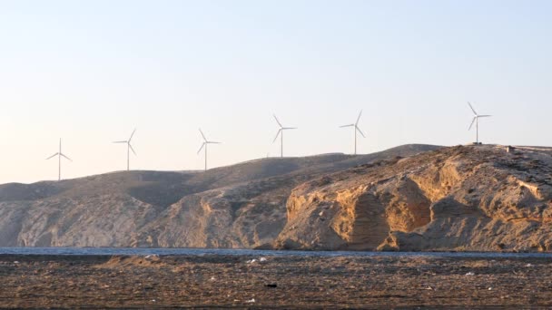 Windturbinestroomgeneratoren aan de oceaankust bij zonsondergang. — Stockvideo