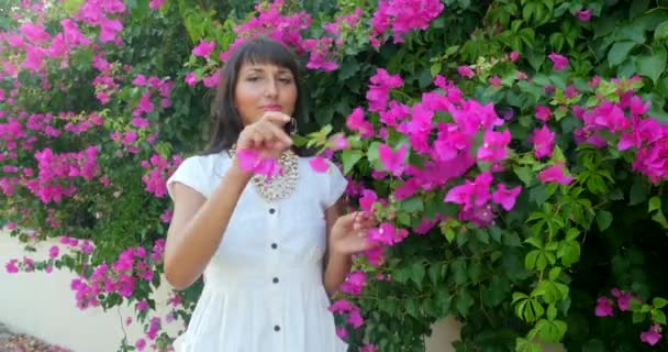 Красива жінка на фоні стіни квітів — стокове відео