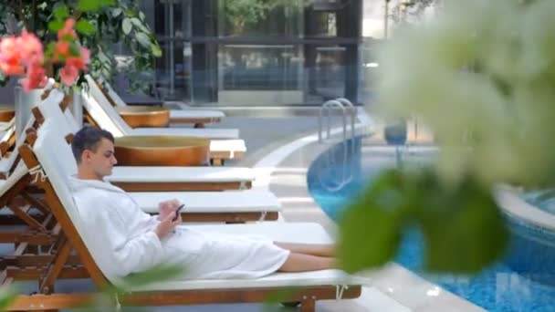 Jongeman in badjas liggend op zonnebank — Stockvideo