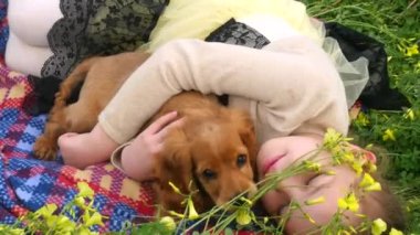 Güzel kız bir köpek yavrusu ile yeşil çim üzerinde yatıyordu