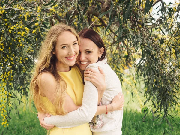 Junge schöne lächelnde Frauen im Frühling australische Goldwattle-Bäume. — Stockfoto