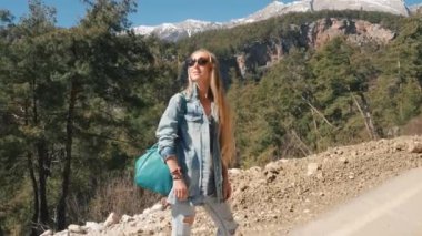 Kot giysiler içinde güzel genç bayan büyük çanta otostop güneşli gün açık havada tutan