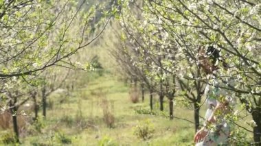 Bahar çiçekleri bahçesinde yürüyen uzun elbiseli güzel bir kadın.
