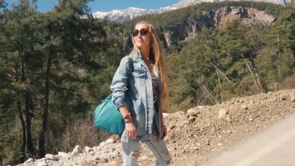 Hermosa joven en ropa vaqueros sosteniendo gran bolso de mano autostop día soleado al aire libre — Vídeos de Stock