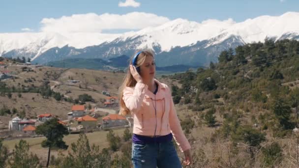 Молодая женщина слушает музыку с наушниками на открытом воздухе — стоковое видео