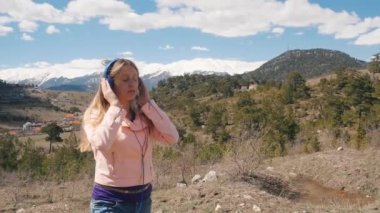 Dışarıda kulaklıkla müzik dinleyen genç bir kadın.