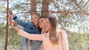 Üç genç kadın cep telefonuyla selfie çekiyor