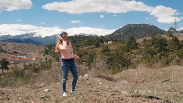 Mujer joven escuchando música con auriculares al aire libre — Vídeo de stock