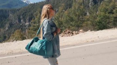 Kot giysiler içinde güzel genç bayan büyük çanta otostop güneşli gün açık havada tutan