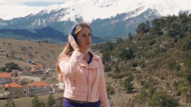 Dışarıda kulaklıkla müzik dinleyen genç bir kadın.