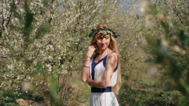 Bahar çiçekleri bahçesinde duran uzun elbiseli güzel bir kadın.