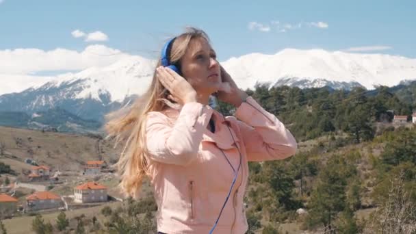 Mujer joven escuchando música con auriculares al aire libre — Vídeo de stock