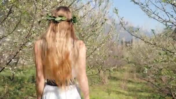 Giovane bella donna in abito lungo a piedi nel giardino fiorito primaverile — Video Stock