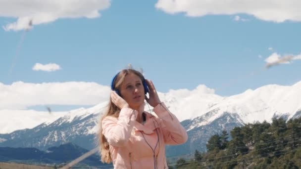 Молодая женщина слушает музыку с наушниками на открытом воздухе — стоковое видео