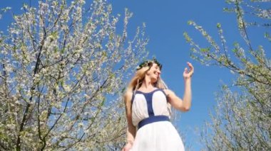 Bahar çiçekleri bahçesinde duran uzun elbiseli güzel bir kadın.