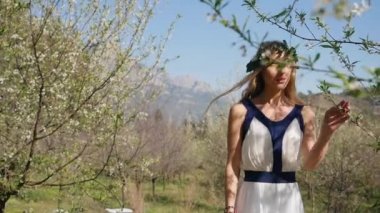 Bahar çiçekleri bahçesinde yürüyen uzun elbiseli güzel bir kadın.