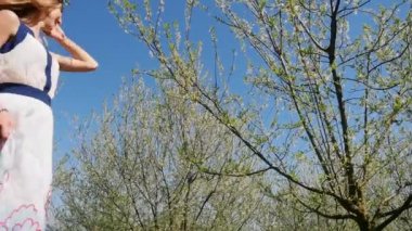 Bahar çiçekleri bahçesinde duran uzun elbiseli güzel bir kadın.