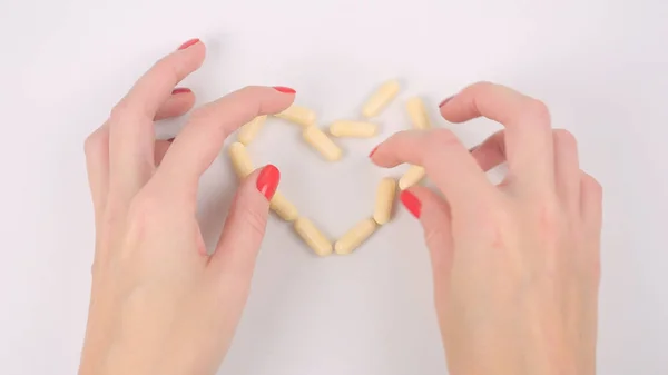 Making heart shape yellow capsule pills on the table