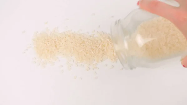 Pouring white rice seeds from glass jar — Stock Photo, Image