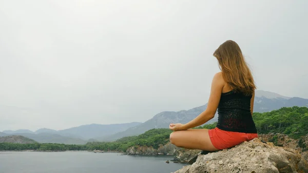 Touriste féminine assise sur un rocher sur un ciel clair et fond de mer calme — Photo