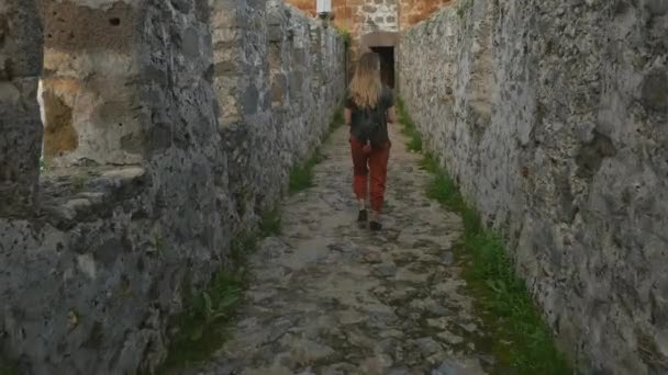 Turista mujer caminando en la antigua pared del castillo para tomar una foto con el mar Mediterráneo tranquilo en el fondo . — Vídeos de Stock