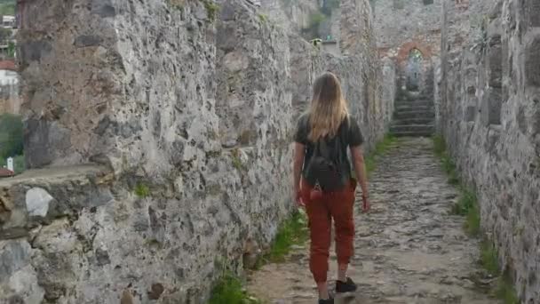 Vrouw toerist wandelen op oude kasteel muur om een foto met kalme Middellandse Zee op de achtergrond te schieten. — Stockvideo