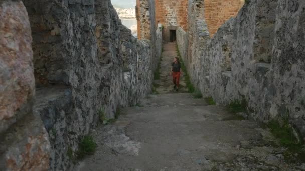 Vrouw toerist wandelen op oude kasteel muur om een foto met kalme Middellandse Zee op de achtergrond te schieten. — Stockvideo