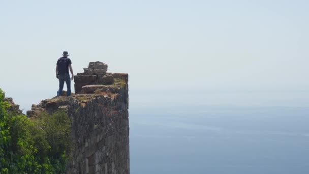 Homme touriste marche sur l'ancien mur du château pour prendre une photo avec la mer Méditerranée calme sur fond . — Video