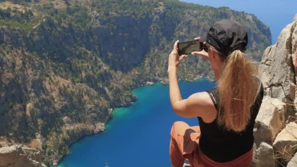 Mujer viajera tomando fotos o videos y disfrutando de una hermosa vista de The Butterfly Valley desde la cima de la montaña — Vídeos de Stock