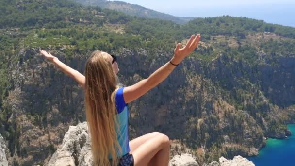 Junge Frau genießt die Freiheit und nimmt ein Sonnenbad mit herrlichem Blick auf das Schmetterlingstal im Hintergrund in der Türkei — Stockvideo