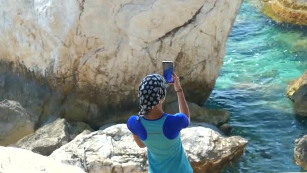 Mujer joven viajera de pie sobre la roca y tomando fotos — Vídeos de Stock