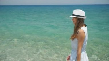 Beyaz şapkalı genç güzel beyaz kız sahil görünümü boyunca yürüyor