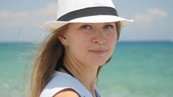 Retrato de joven hermosa chica caucásica con sombrero blanco en la playa vista costera — Vídeo de stock