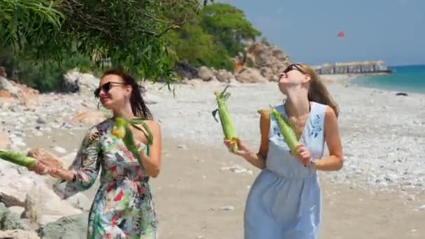 Jóvenes mujeres bastante felices con ganar de maíz en sus manos bailando baile divertido en la playa — Vídeos de Stock