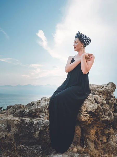 Mulher muçulmana bonita jovem, atraente em vestido preto longo sentado na pedra perto da torre de Hidirlik — Fotografia de Stock