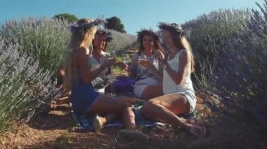 Dört genç kadın lavanta tarlasında şarapla piknik yapıyor..