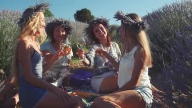 Dört genç kadın lavanta tarlasında şarapla piknik yapıyor..