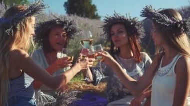 Dört genç kadın lavanta tarlasında şarapla piknik yapıyor..