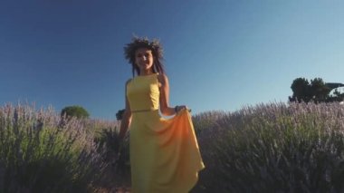 Lavanta tarlasında elinde buket tutan çelenkli genç bir kadın.
