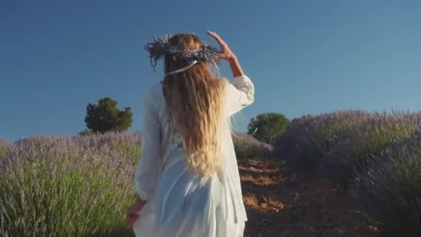 Jonge vrouw in krans gelukkig rennend in lavendelveld — Stockvideo