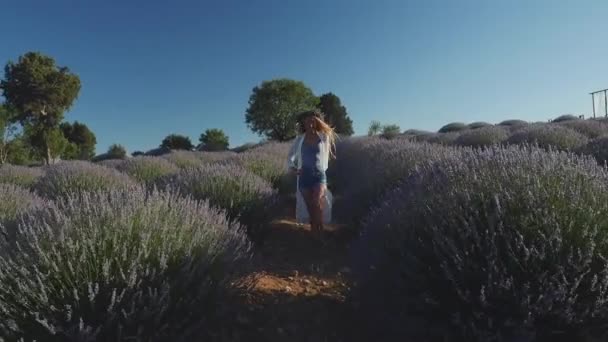 Молодая женщина в венке ходит быстро, как модель на лавандовом поле — стоковое видео