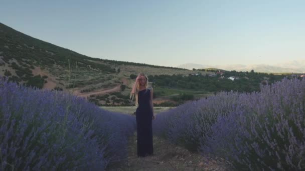 Jonge vrouw in casual kleding staan in het lavendelveld — Stockvideo