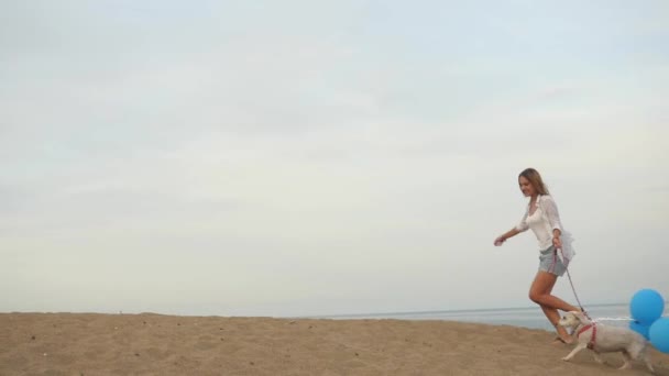 Девушка бежит с воздушными шарами вместе с собакой — стоковое видео