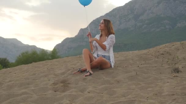 Mujer joven sentada en la playa con globo — Vídeo de stock