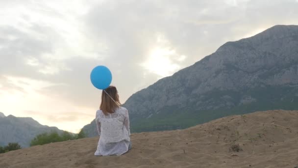 Mladá žena sedí na pláži s balónem — Stock video